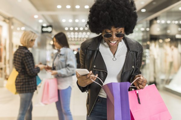 Dia do Consumidor: jovem mulher abrindo as sacolas de compras