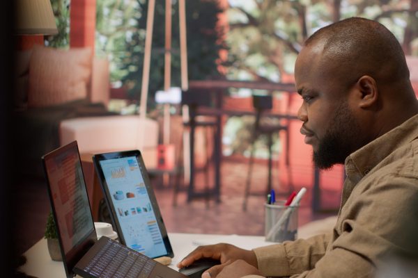 Jovem negro trabalhando no computador com ferramentas de comunicação