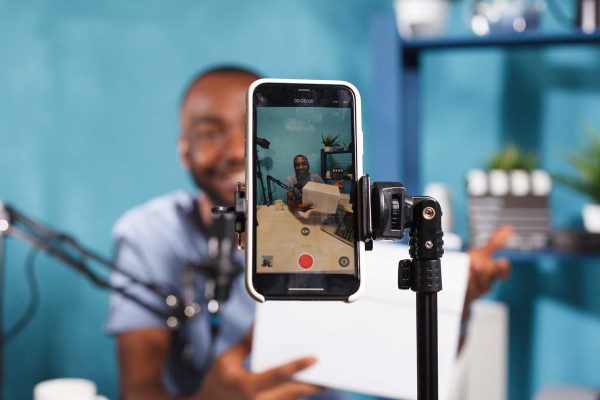 Jovem homem negro fazendo produção audiovisual no celular