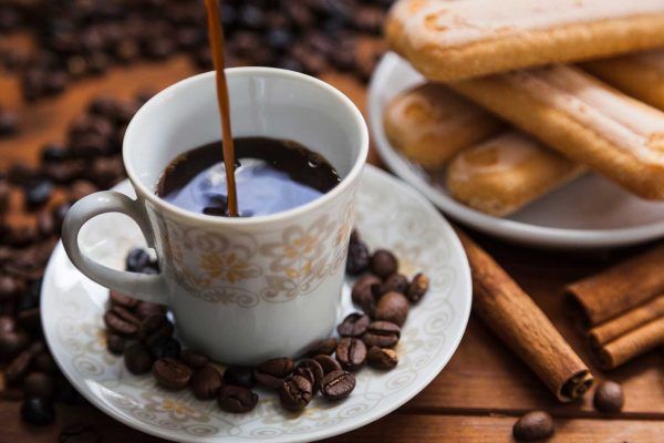 Café caindo na xícara e grãos ao redor