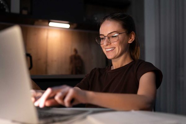 Mulher escrevendo no notebook e sorrindo