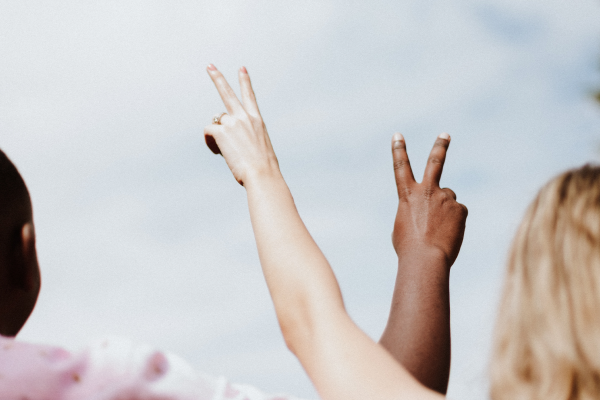Duas pessoas cruzando suas mãos com o símbolo da paz em comemoração ao Dia Internancional dos Direitos Humanos