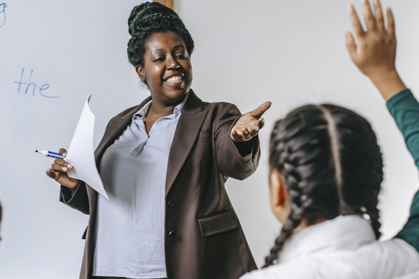 Professora negra em sala de aula lecionando pars seus alunos sobre o antirracismo.
