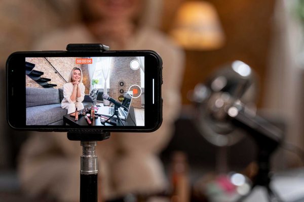 Smartphone no tripé enquadrando a mulher que irá gravar o vídeo com roteiro